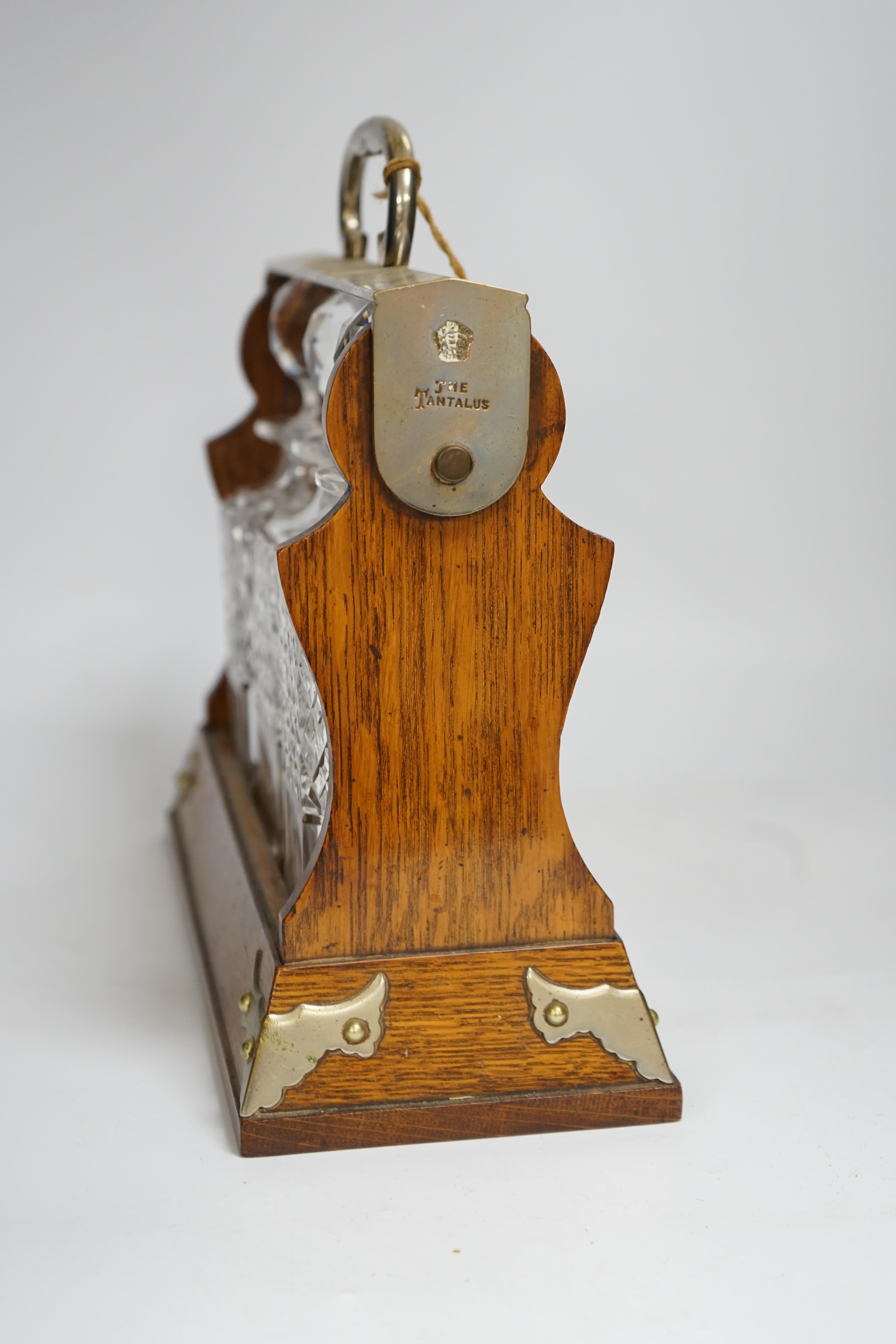 A Betjemann’s patent oak three bottle tantalus with key, 32cm wide